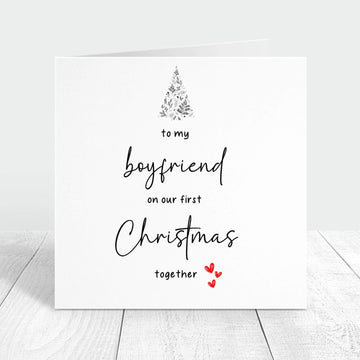 Personalised Christmas card for boyfriend with the message "To my boyfriend on our first Christmas together," featuring a festive tree and red hearts.