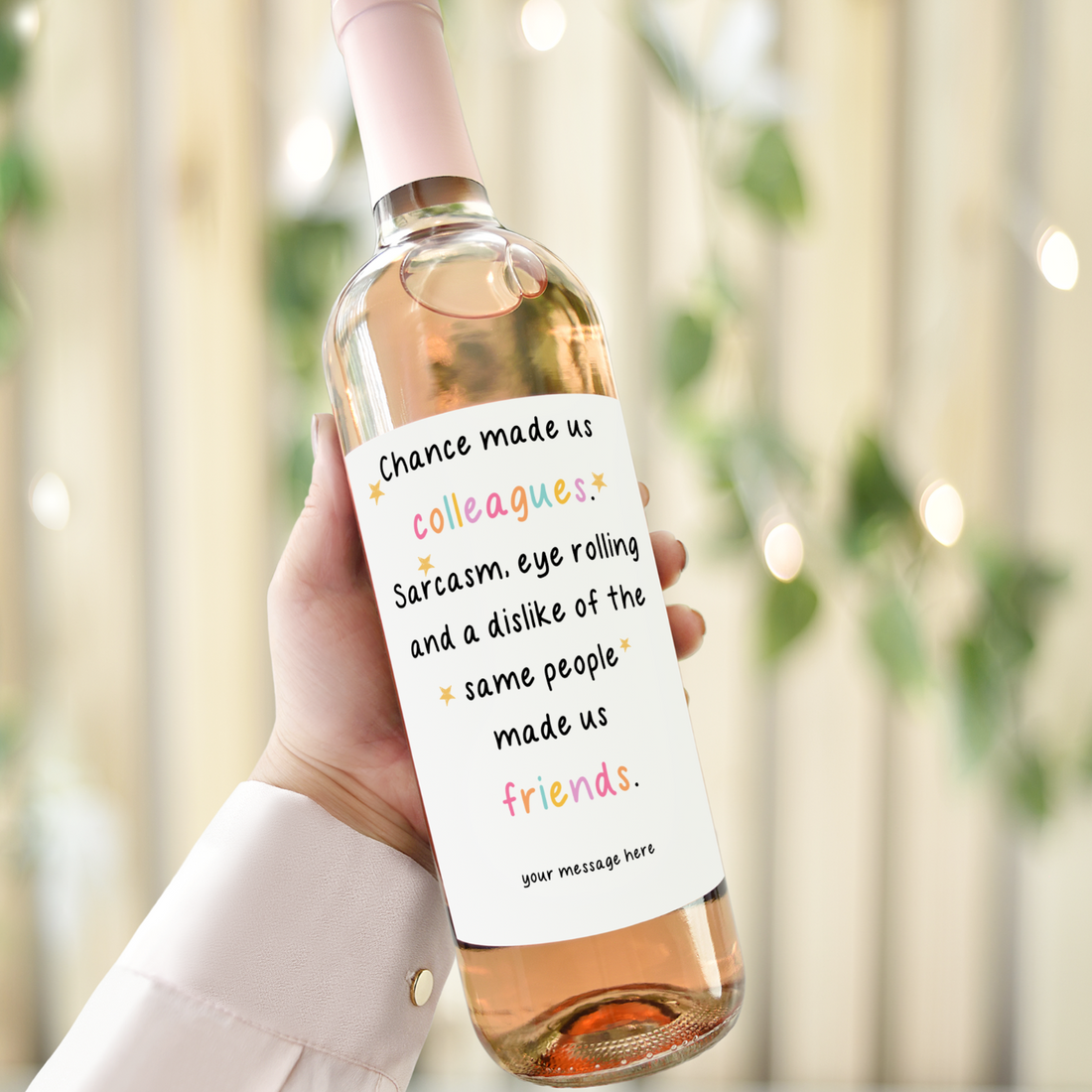 Personalised wine label reading "Chance made us colleagues, sarcasm and shared dislikes made us friends" on a wine bottle held in hand.
