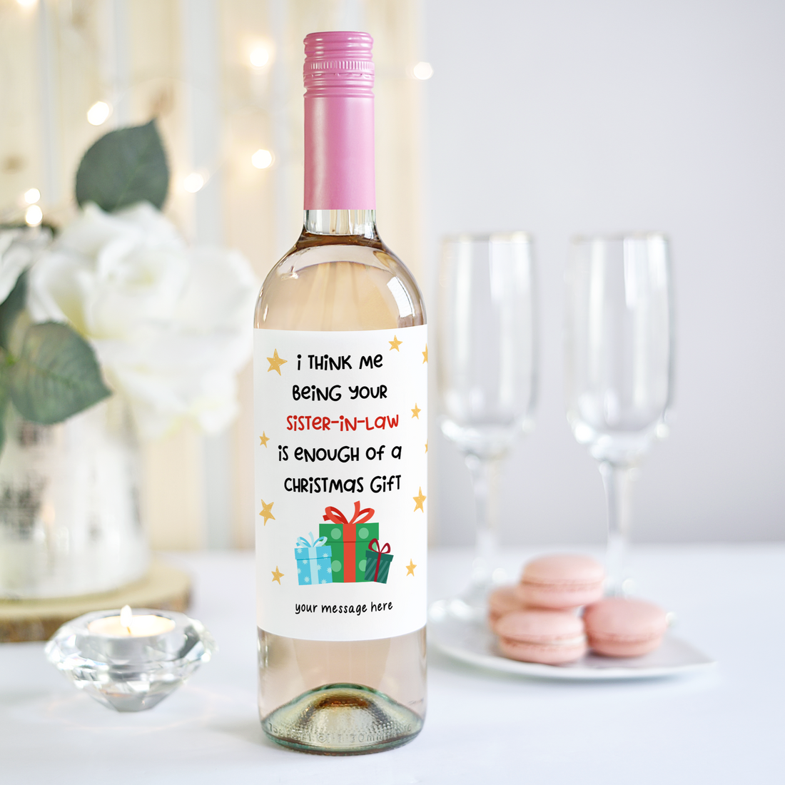 Hand holding a wine bottle with a humorous Christmas label for a sister-in-law, featuring stars and a festive gift graphic.