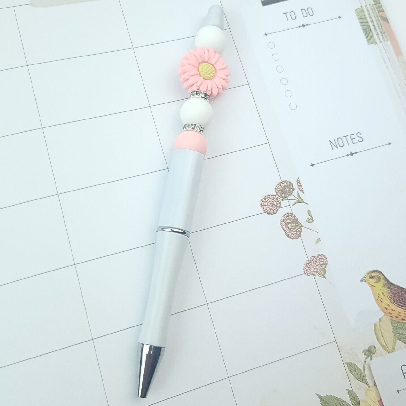 beadable pen with pink daisy and white beads, writes in black