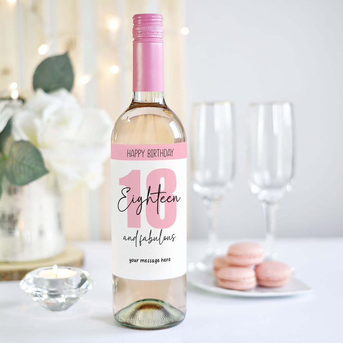 Personalised 18th birthday wine label with 'Eighteen and Fabulous' design in pink and white, held against a party backdrop.