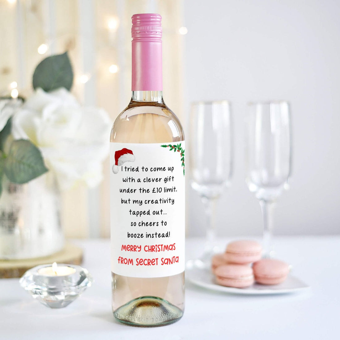 Wine bottle with a humorous Secret Santa label reading 'I tried to come up with a clever gift under the £10 limit, but my creativity tapped out... so cheers to booze instead! Merry Christmas from Secret Santa.'